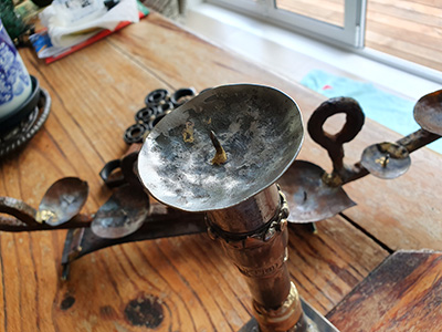 An image of a recycled metal object candlestick holder. The holder in the fopreground is from recycled tool sockets welded together, and steel from recycled library shelves, cut shaped and drilled for the nail to position the candle on. Welded by Graham Hughes of McKinley Rd Creatives using a variety of welding processes