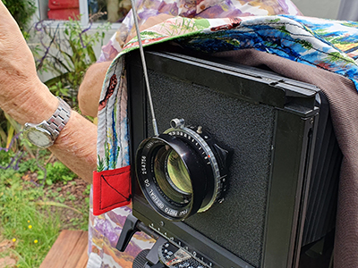 Colin Booth photographer working with large format cameras, shooting paper negatives in camera. he is measure light for an exposure time.