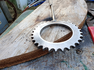 A detail of the head piece of a flagpole welded to the very top of the flagpole at Mc KinleyRd Creatives. The welded piece is a recycled sprocket from a machine